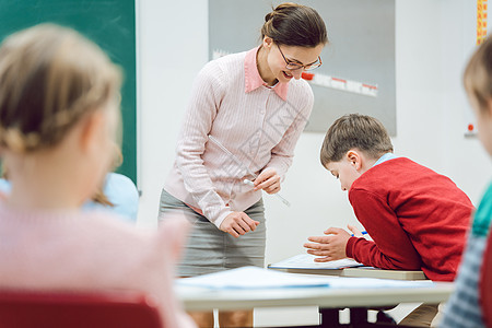 女教师在课堂上与学生交谈房间工作教育老师女士孩子们学习小学文法木板图片