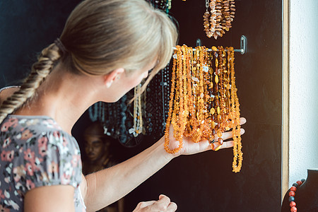 女人看着一条由琥珀制成的项链售货员宝石店铺帮助文员珠宝石头服务女士作坊图片