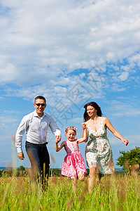 快乐的一家人夏天在草地上奔跑幸福微笑女儿父亲爸爸活动女士蓝色裙子童年图片