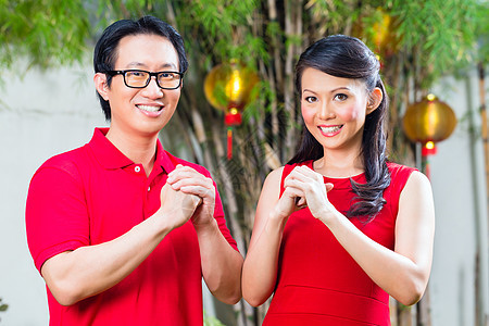 庆祝中国新年的一对夫妇庆典朋友们问候语花园传统男人红色眼镜运气衬衫图片