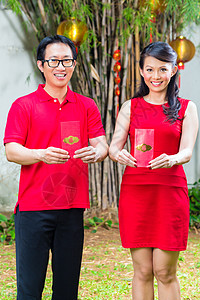 庆祝中国新年的一对夫妇礼物灯笼花园传统展示朋友们红色信封男人女士图片