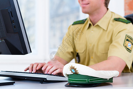 在派出所办公服务台工作的警察干事部门键盘警官男性警察局安全电脑帽子写作男人图片