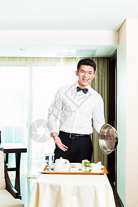 亚裔中国客房服务员在酒店为客人提供食品送货成人托盘员工奢华房间食物商业男人套房图片