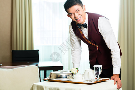 亚裔中华客房服务员在酒店供餐盘子食物男性管家奢华套房工作员工职业服务图片
