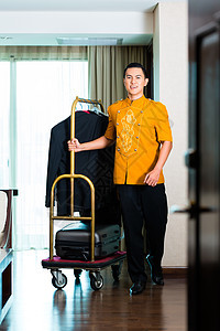 亚洲钟男孩拉箱子面包车的肖像员工手提箱房间酒店成人行李搬运工服务男人旅馆图片