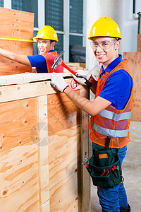 工人用铁锤和钉子特写一个木箱职业盒子建筑检查木头送货锤击头盔指甲工作图片