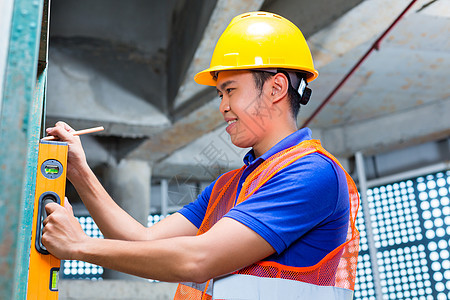 建筑工地上的建筑工或工人控制墙房子工作围墙员工建设者气泡头盔安全帽测量工匠图片