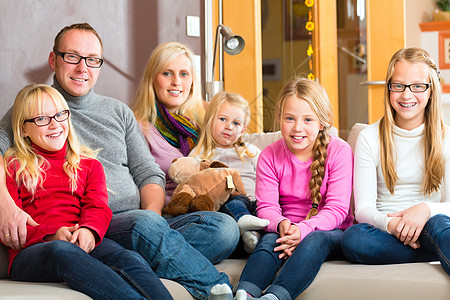 家庭一起坐在沙发上父母母亲女士爸爸姐妹生活房地产女儿们孩子们眼镜图片