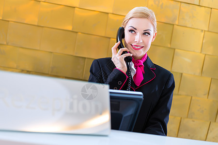 在前台有电话的旅馆接待员服务女士奢华办公室桌子微笑电脑客人接待职业图片
