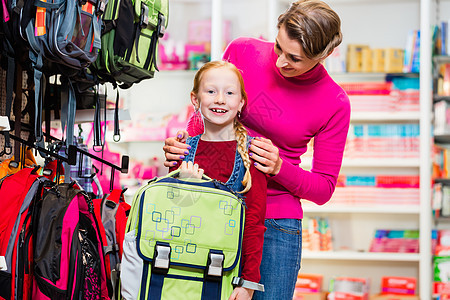 母亲和孩子在商店购买书包或袋子购物店铺学习女儿零售瞳孔学生用品女士学校图片