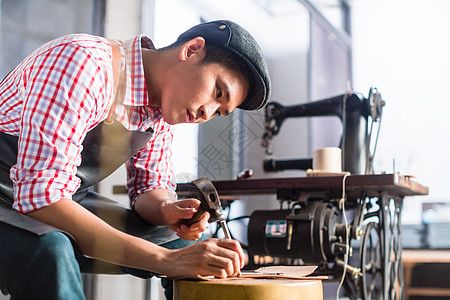 皮革车间中的亚洲鞋或腰带制造器男人工具鞋匠制造业作坊职场锯床生产工人工作图片