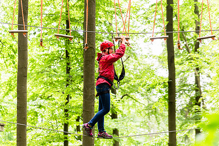 儿童在高绳绳课程中攀登平台绳索冒险女孩木头运动森林头盔闲暇公园绿色图片