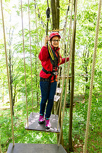 少女在高绳索课程或学术讲座中攀爬冒险头盔女孩青少年闲暇森林公园绿色行动高空图片