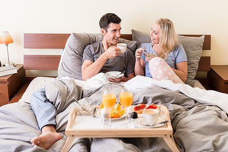 快乐的年轻夫妇 喝咖啡和橙汁福利微笑咖啡卧室女士枕头果汁放松早餐蜜月图片