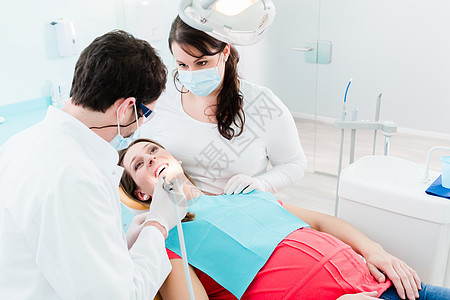 使用钻头治疗女病人的牙科医生外科牙科团队办公室牙医医生牙齿手术护理人员同事图片