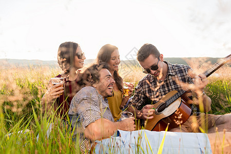 坐在草地上弹吉他玩吉他的年轻人歌曲男人音乐女性女孩们啤酒国家草原情绪女孩图片