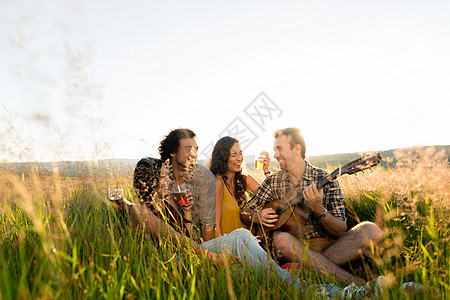 坐在草地上弹吉他玩吉他的年轻人女孩酒精男生日落饮料男人音乐国家情绪女性图片