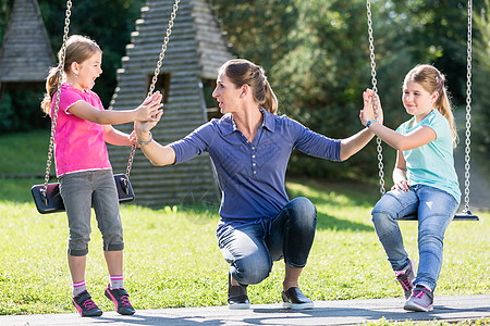 有两个女孩和母亲的家庭在游乐场玩耍公园幸福闲暇娱乐感情活动微笑乐园学校冒险背景图片