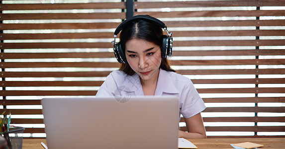 年轻美少女使用膝上型计算机学习或创业者在家中用笔记笔记和笔记电脑工作图片