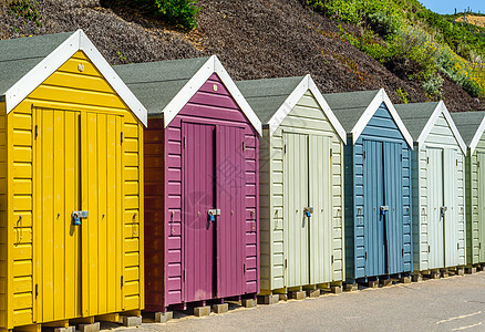 海滩上有彩色房屋 通往夏季小屋 海边地点的多彩门家庭海滨太阳行人植物庇护所蓝天居住衣服假期图片
