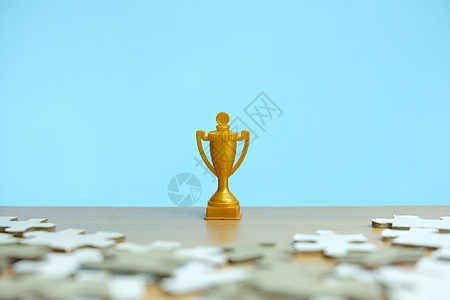 一个金色的奖杯矗立在一堆拼图之间人士解决方案冠军商业胜利挑战优胜者金子障碍插图图片