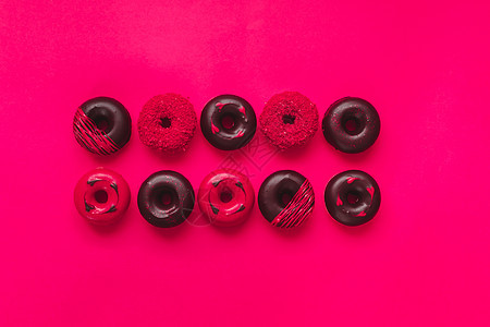 什锦情人节甜甜圈 带有巧克力 糖霜和糖的迷你甜甜圈洒在充满活力的红色背景上 快乐情人节概念图片