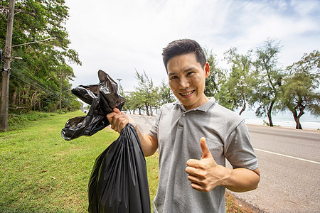 绿色志愿服务 乐观的两名志愿者在公园里拿着垃圾袋帮助捡垃圾 他们正在捡垃圾并将其放入黑色垃圾袋中 生态保护理念合作生活方式活动青图片