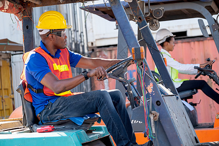 非洲裔美国工头或货运集装箱工人驾驶货车 看着他的女同事也在工作区开车 工业支持系统帮助员工绩效理念图片