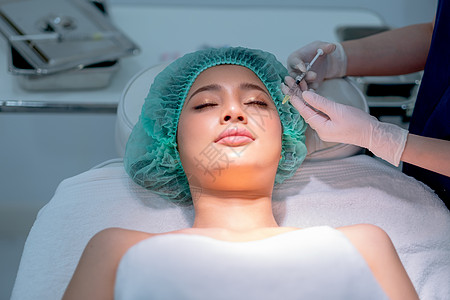 美容诊所工作人员紧握着针筒和含有化学剂的针头 供在诊所的亚洲客户妇女进行美容治疗图片
