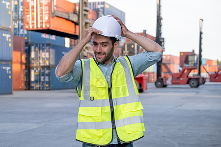 Foreman工程师或货物集装箱工人持硬帽 站在起重机和堆叠航运的前面 后勤船厂管理系统和安全概念 (三) 运输工具背景