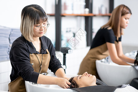 美丽的女人在美容院店里被年轻的理发女郎洗了头 她看起来放松而快乐 美丽的头发和身体护理业务 以良好的外观概念图片