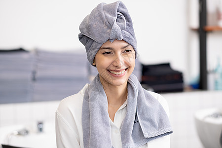 美丽的高加索女人的肖像 用毛巾遮盖头部 头发笑着向右看 在美容院店里待着呢图片