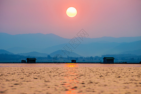 日落时太阳照在山上和湖上辉光农村旅行地平线海岸风景日落钓鱼热带火花图片