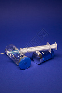 两个没有标签的透明疫苗瓶小瓶 医用注射器注射针 在蓝色背景上隔离 冠状病毒疫苗 COVID19 的开发 治愈 世界研究竞赛安瓶药图片