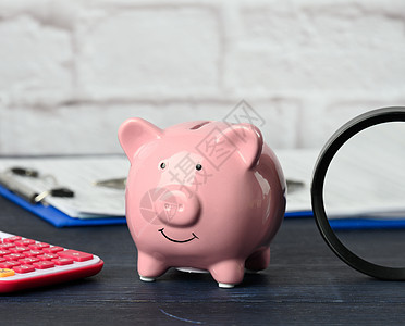 粉红小猪银行 计算器和放大器放在桌上 储蓄 预算规划图片