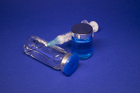 两个没有标签的透明疫苗瓶小瓶 医用注射器注射针 在蓝色背景上隔离 冠状病毒疫苗 COVID19 的开发 治愈 世界研究竞赛药理药图片