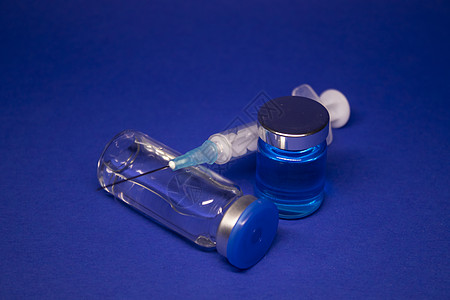 两个没有标签的透明疫苗瓶小瓶 医用注射器注射针 在蓝色背景上隔离 冠状病毒疫苗 COVID19 的开发 治愈 世界研究竞赛横幅科图片