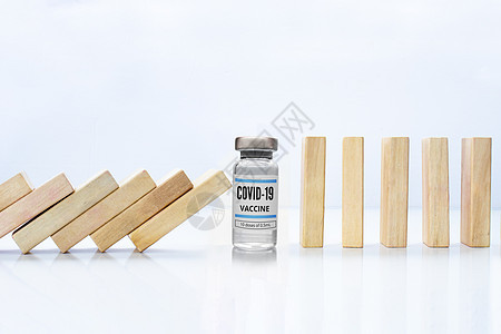 木块多米诺骨牌效应用 Covid-19 小瓶疫苗阻止掉落 旁边是站立的木块概念 Covid-19 疫苗阻止危机和风险 保护概念图片
