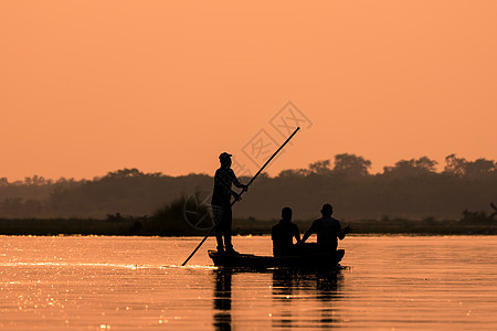 船上的男人们在河边的轮椅上阳光流量日落寂寞闲暇橙子独木舟渔夫反射运动图片