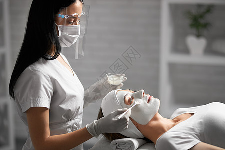 美容师为病人做清洁脸部和化妆品背景图片