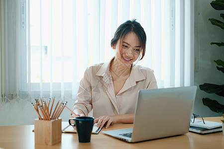 一个快乐的女人在她的笔记本电脑上 专注在网络研讨会上图片