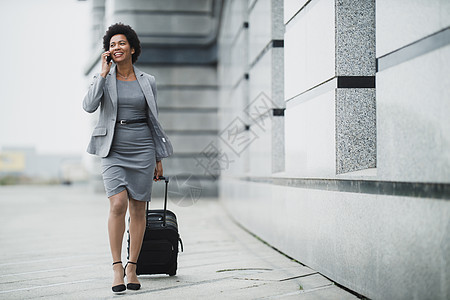 商业妇女走一条路成功人士飞机场商务旅行黑色导演快乐通勤者行李图片