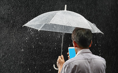 年中亚洲男性持雨伞和电话在夜间下雨时使用图片