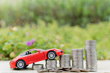 绿色自然背景模糊的硬币堆上的红色汽车 存钱和投资概念订金储蓄银行债务利润安全资产贷款小猪商业图片