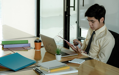 处理文件的亚洲商务人士看起来专注于桌上的公文包图片