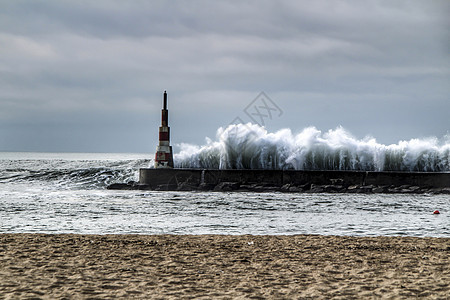 巨大的波浪冲破断裂水和灯塔运动海洋气候支撑休息天空灾难海岸海景码头图片