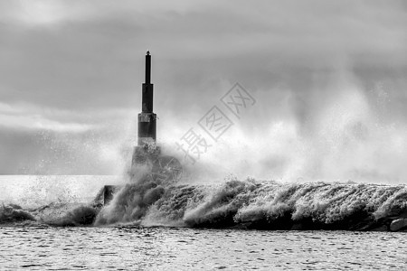 巨大的波浪冲破断裂水和灯塔戏剧性碰撞天空天气运动灾难海洋气候风暴支撑图片