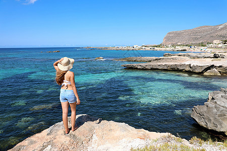 岩石岛上的旅行者女孩风景与结晶海水 年轻女子在意大利西西里岛的法维尼亚纳岛享受假期图片