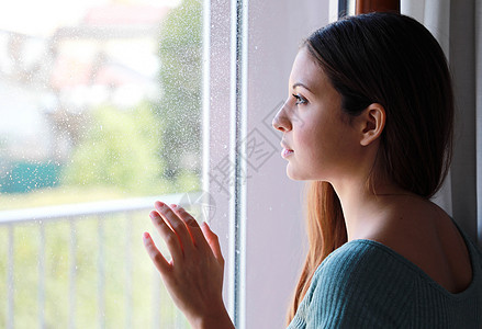 忧郁悲伤的年轻女子在雨天从家里窗外看望着窗户 专注模特眼 室内照片图片