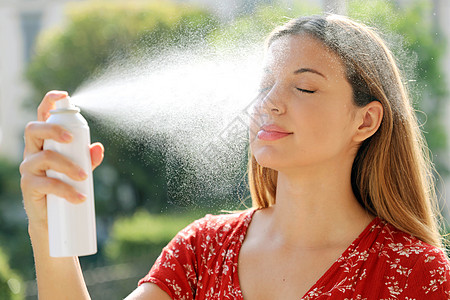 年轻女子在室外的脸上涂抹热水 用于护肤 定妆 帮助皮肤刺激 发红和蚊虫叮咬的温泉水图片